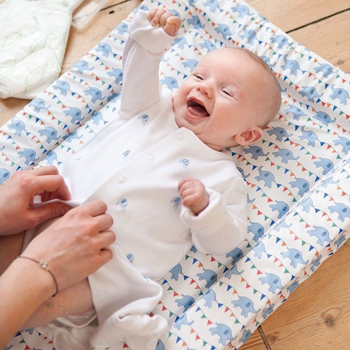 happy baby getting changed in a baby change mat 