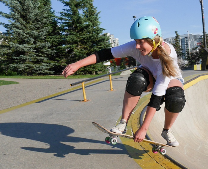 picture of a woman skateboarding with protective gear in a park 