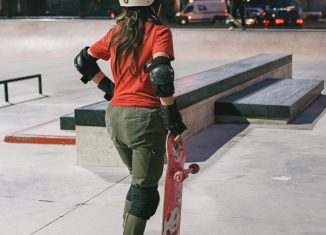 picture of a girl holding a skateboard, wearing protective gear