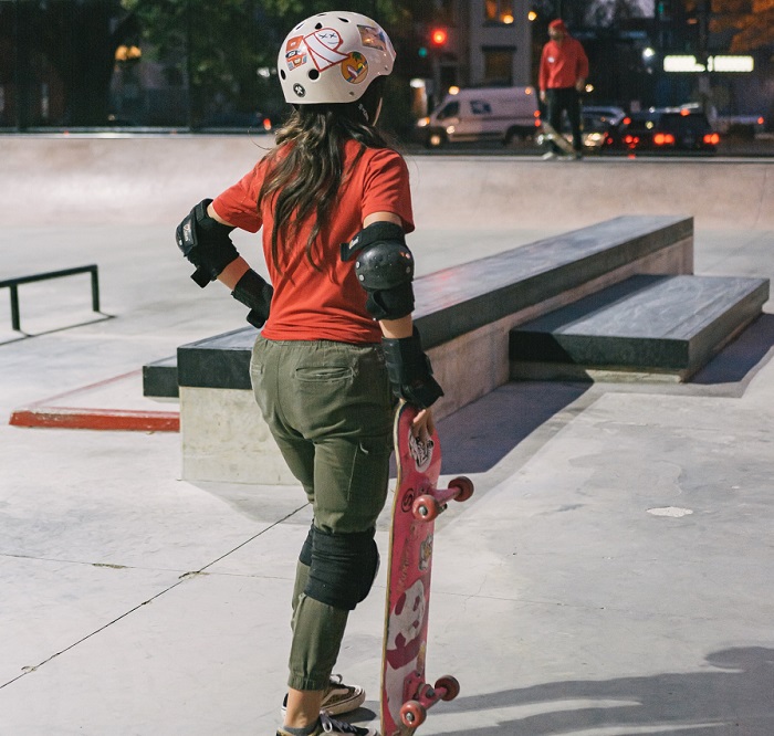 picture of a girl holding a skateboard wearing protective gear