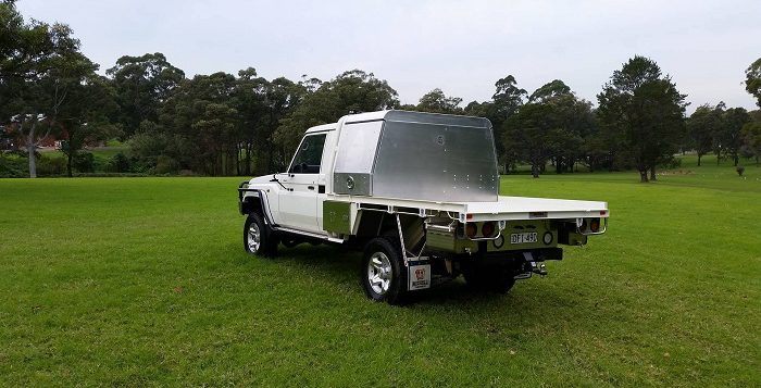picture of an ute with mini aluminum canopy on grass beside trees