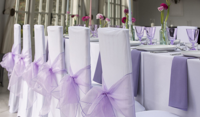 white chair covers with purple ribbons