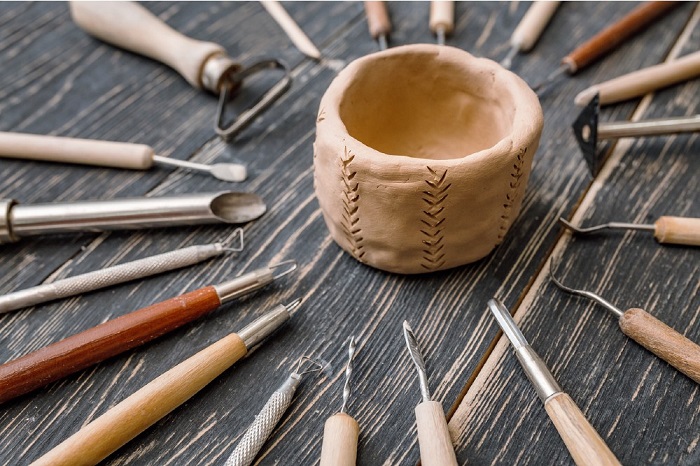 a ring of clay tools around a miniature clay sculpture in a cup form