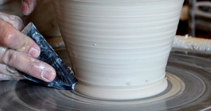 a potter using a clay rib on his ceramic vase
