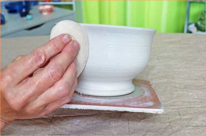 potter using a clay sponge to dry op his ceramic sculpture